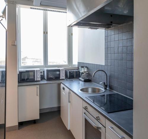 eine Küche mit einem Waschbecken und zwei Fenstern in der Unterkunft Raahe Apartments in Raahe