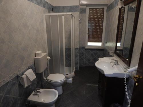 uma casa de banho com 2 lavatórios, um WC e um espelho. em albergo massimo em Loano