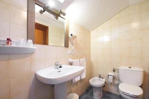 a bathroom with a sink and a toilet and a mirror at La Casona de Mestas in Ponga