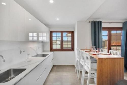 una cucina bianca con un tavolo e delle sedie di Apartamento El Unicornio De Paula By Paramount Holidays a Candelaria