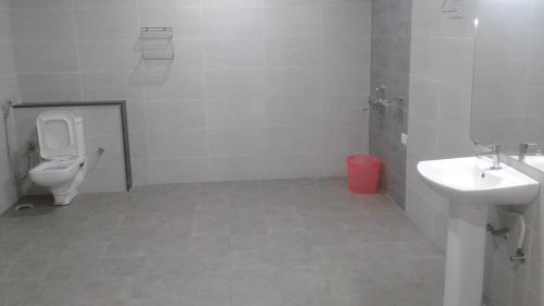 a white bathroom with a toilet and a sink at RK - Inn Premium Suites in Bengaluru
