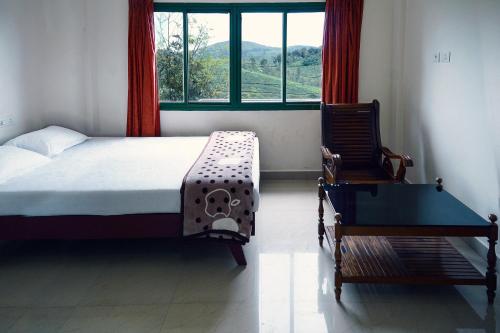 a bedroom with a bed and a table and a window at Vagamon Tea County in Vagamon