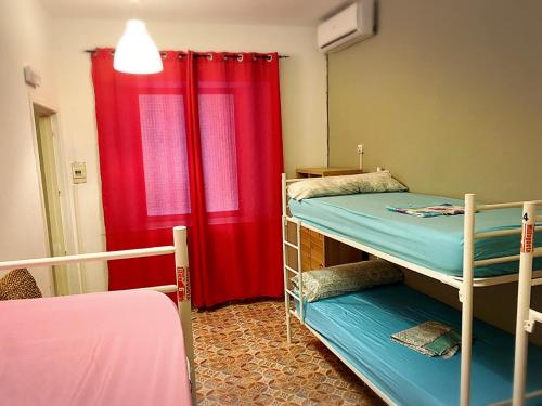 een kamer met 2 stapelbedden en een rood gordijn bij Cathedral Malaga Hostel in Málaga