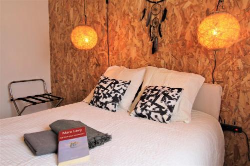 a bed with two pillows and a book on it at Les Bastidons de l'Isle - Le Saumane - 3 étoiles in L'Isle-sur-la-Sorgue