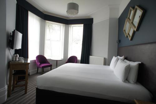 ボーンマスにあるApplewood Hotelのベッド、デスク、窓が備わるホテルルームです。