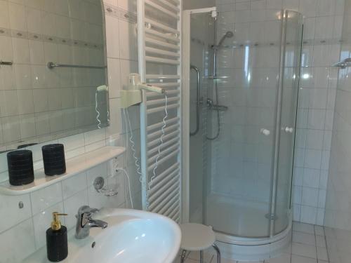 ein weißes Badezimmer mit Waschbecken und Dusche in der Unterkunft Weinhaus Hotel in Norddeich