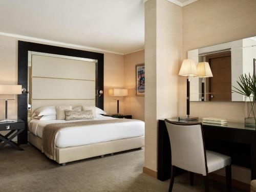 a hotel room with a bed and a desk and a desk at Galaxy Iraklio Hotel in Heraklio Town