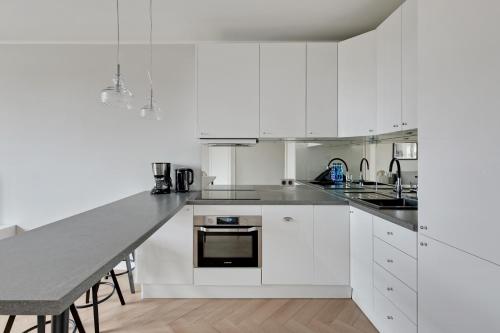a white kitchen with white cabinets and a table at Downtown Apartments City Center Tartaczna in Gdańsk