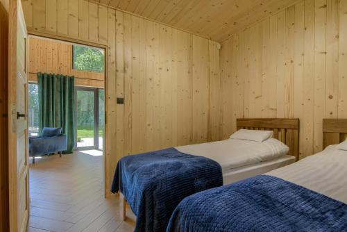 two beds in a room with wooden walls at Ośrodek Wypoczynkowy Zapach Drewna Resort & Lake in Barczewo