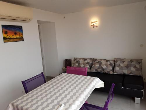 un salon avec un canapé, une table et des chaises dans l'établissement Appartement les mouettes du Cap d'Agde, au Cap d'Agde