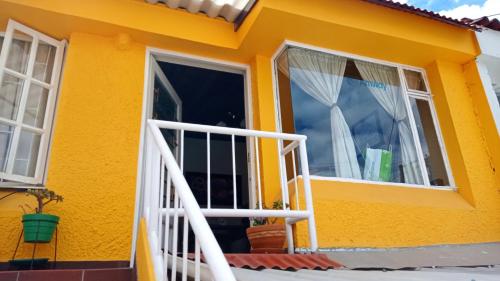 Habitación 5 minutos aeropuerto في بوغوتا: منزل أصفر مع باب أبيض ونوافذ