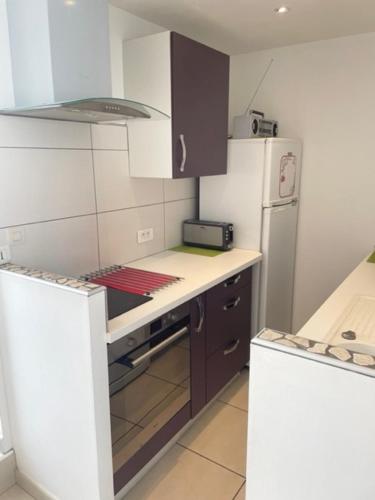 une cuisine avec une cuisinière et un réfrigérateur dans l'établissement Appartement les mouettes du Cap d'Agde, au Cap d'Agde