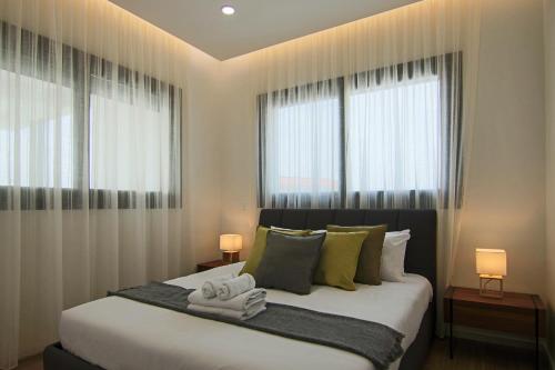 a bedroom with a large bed with two windows at Phaedrus Living: City View Anna Residence 101 in Limassol