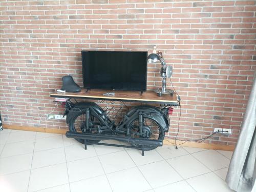 a desk with a computer on top of a motorcycle against a brick wall at La pacheca in Lazise