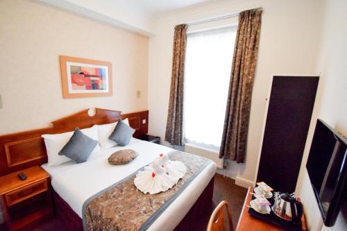 una camera d'albergo con letto e finestra di Pembridge Palace Hotel a Londra