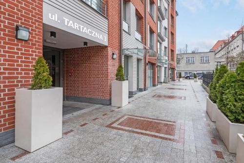 un callejón vacío con macetas en un edificio de ladrillo en Tartaczna Apartments City Center & Parking by Downtown Apartments, en Gdansk