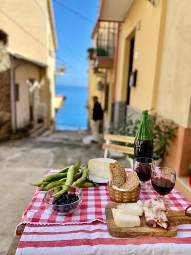 a picnic table with bread and vegetables and a bottle of wine at La Casetta In Centro - Holiday House in Scilla
