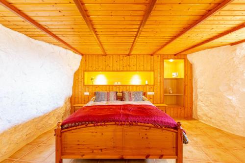 Cama en habitación con techo de madera en La Cueva de Tito-Casa Cueva en plena naturaleza, en Santa Brígida