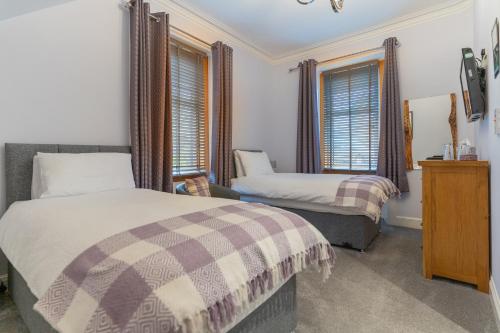 een slaapkamer met 2 bedden en 2 ramen bij Galvelbeg House self catering apartment in Crieff