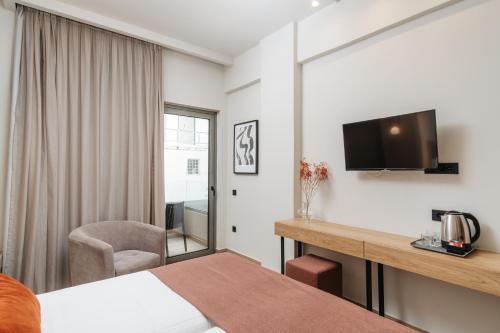 a hotel room with a bed and a desk and a tv at The City Hotel & Suites in Rethymno