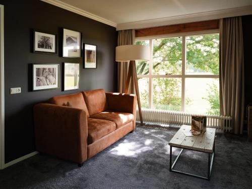 a living room with a brown couch and a window at Landgoed De Holtweijde in Lattrop