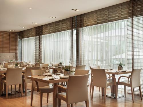 a restaurant with wooden tables and chairs and large windows at Galaxy Iraklio Hotel in Heraklio