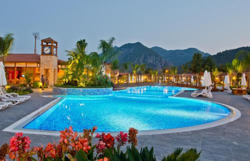 einen Pool in einem Resort mit einem Uhrturm in der Unterkunft Kimera Lounge Boutique Hotel & Spa in Cıralı