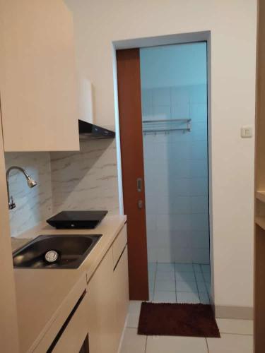 a kitchen with a sink and a glass door at Apartemen MAJ at Ecohome Citra Raya in Nalagati