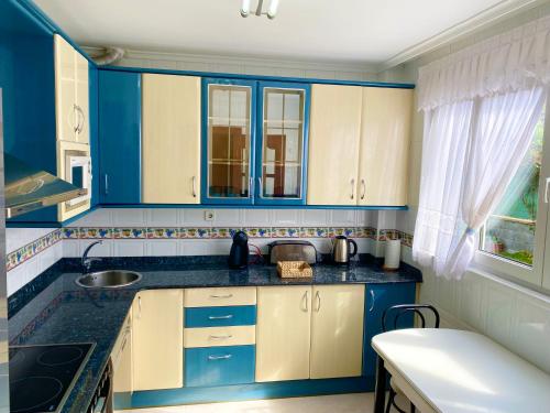 una cocina con armarios azules y blancos y fregadero en Casa de Anmar casa independiente con jardín, Ajo, en Ajo
