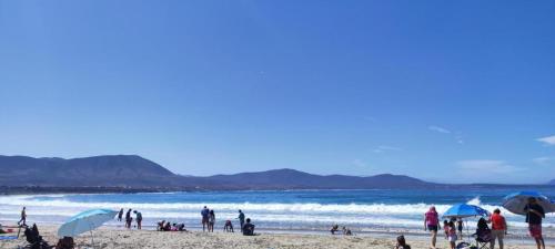 a group of people on a beach with umbrellas at Departamento a pasos de playa Los Molles in Los Molles