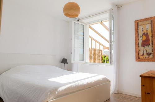 une chambre blanche avec un lit et une fenêtre dans l'établissement Vacances en famille a 250m de la mer a Penmarch, à Penmarcʼh