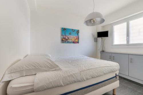 a white bedroom with a bed and a window at Le Grain d'or in Cannes