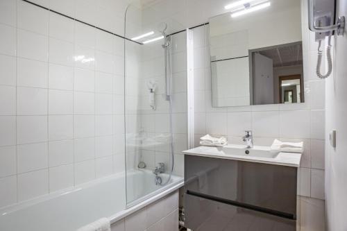 a white bathroom with a sink and a shower at Residhotel Le Grand Prado in Marseille