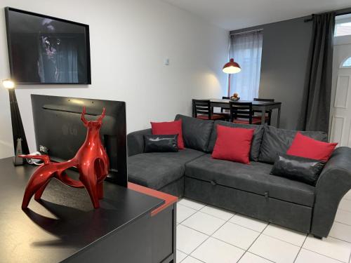 a living room with a grey couch and red pillows at Très bel Appartement cosy proche de la gare et de l'hôpital - IMMOMMER in Orval