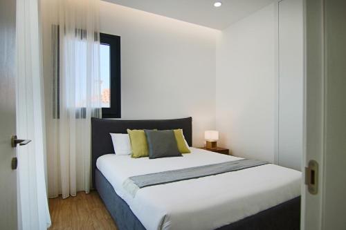 um quarto com uma grande cama branca com almofadas amarelas em Phaedrus Living: City View Anna Residence 102 em Limassol