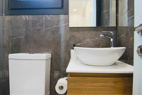 een badkamer met een wastafel, een toilet en een spiegel bij Phaedrus Living: City View Anna Residence 102 in Limassol
