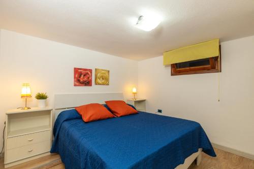een slaapkamer met een blauw bed met 2 oranje kussens bij Casa l'Ulivo in Santa Maria Navarrese