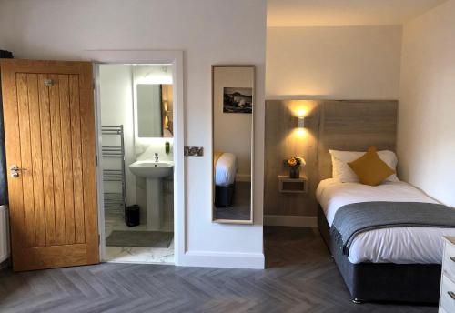 um quarto com uma cama, um lavatório e um espelho em McNaughton Guestrooms em Ballymena