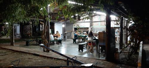 a group of people sitting at tables in a room with trees at Cabañas Los Troncos in Ituzaingó