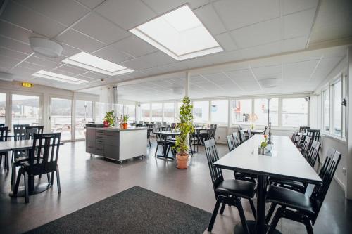 a large room with tables and chairs and windows at Kajkanten Restaurang B&B in Köpmanholmen