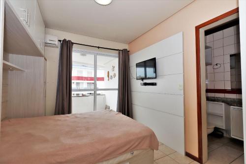 1 dormitorio con 1 cama, TV y ventana en Linda vista para o mar e wi-fi - HB29F, en Florianópolis