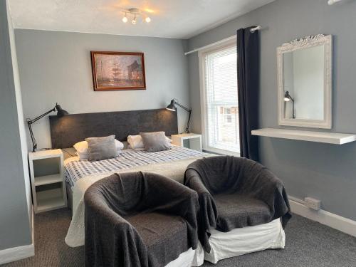 a bedroom with a bed with two chairs and a mirror at Marlborough Hotel in Shanklin