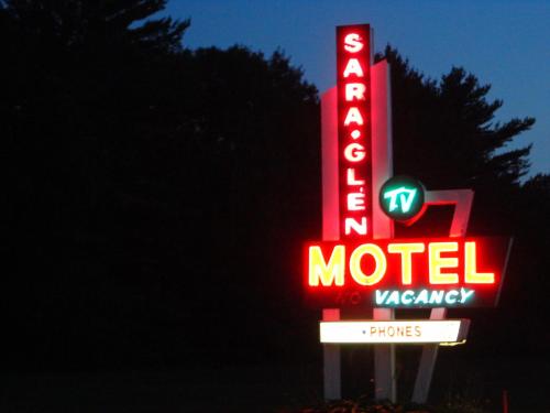 a neon motel sign in front of a dark at Sara Glen Motel - Saratoga Springs-Glens Falls in Saratoga Springs
