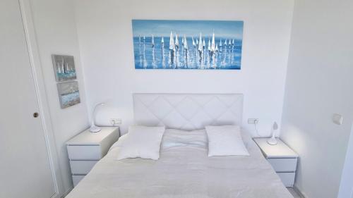biała sypialnia z łóżkiem i 2 szafkami nocnymi w obiekcie Slyline 40 Lujoso apartamento de 1 dormitorio - Muy soleado w mieście Benidorm