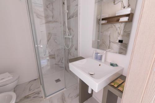 a white bathroom with a shower and a sink at Pietra Bianca Residence in Numana