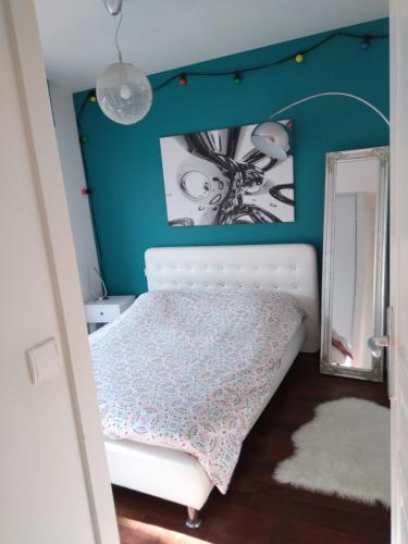 a bedroom with a white bed and a blue wall at Joli T2 proche plages in Bidart