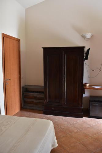 a bedroom with a wooden cabinet and a bed at Giardini Malaspina in Bosa