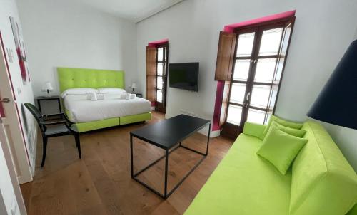 1 dormitorio con 1 cama y 1 sofá verde en Ritual Alameda Suites en Sevilla