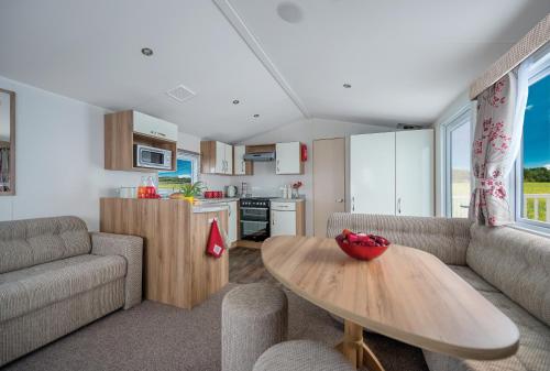 a living room with a table and a kitchen at Tehidy Holiday Park in Illogan