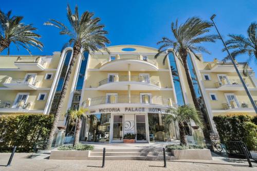 a hotel with palm trees in front of it at Victoria Palace Hotel & Zen Wellness in Gallipoli